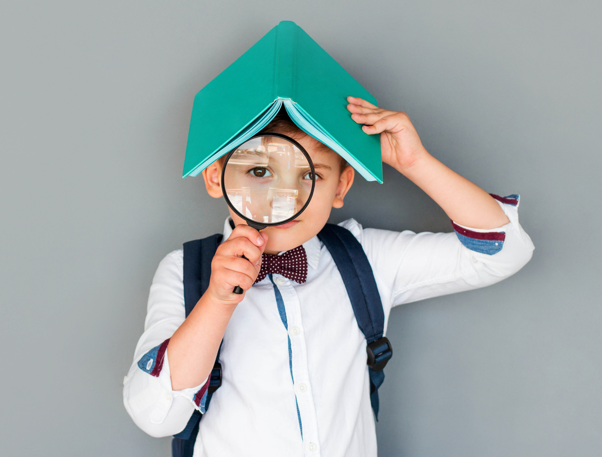 Funny little boy looking through a magnifying glass.